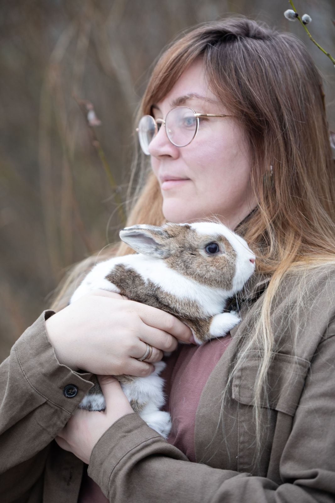 Woman with glasses cuddling a small brown and white rabbit